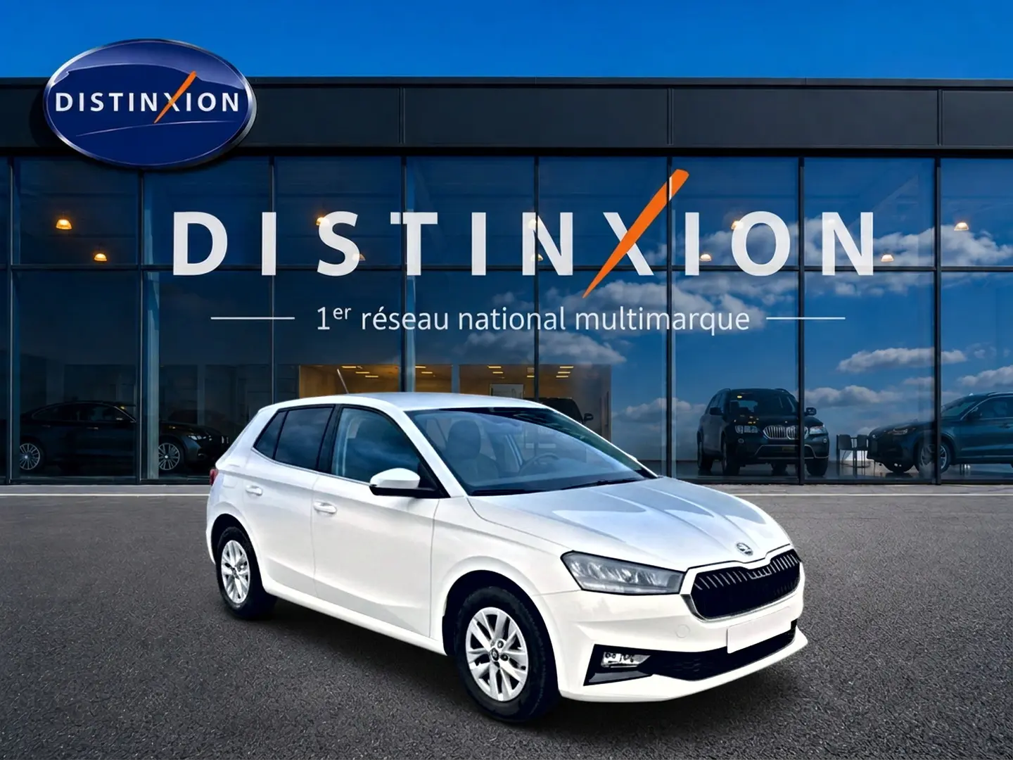 SKODA Fabia blanche vue en 3/4 avant droit, avec jantes alu et calandre noire devant un showroom Distinxion.