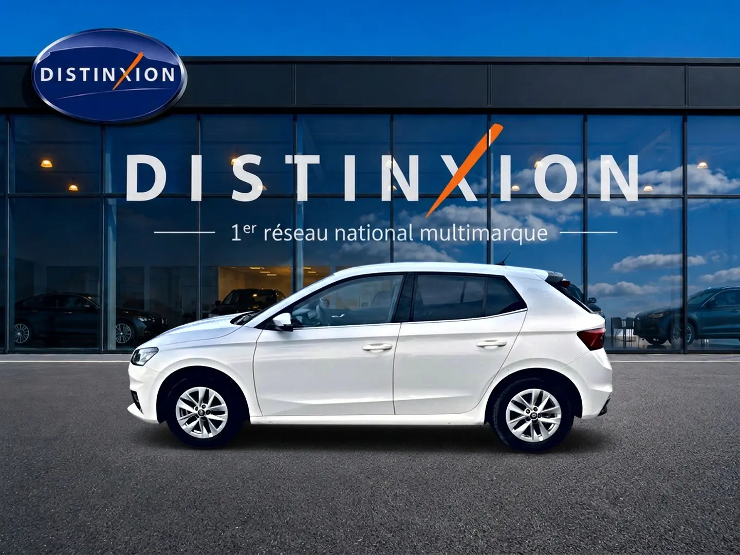 Profil côté gauche d'une Skoda Fabia blanche 2025 garée devant une vitrine avec logo Distinxion.