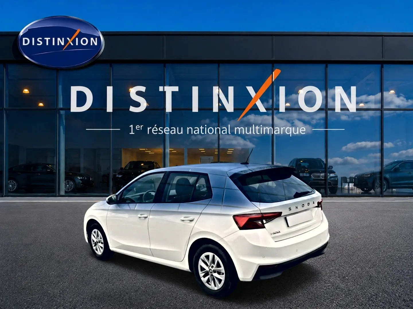 Vue 3/4 arrière droite d'une Skoda Fabia blanche 2025 garée devant une vitrine Distinxion.