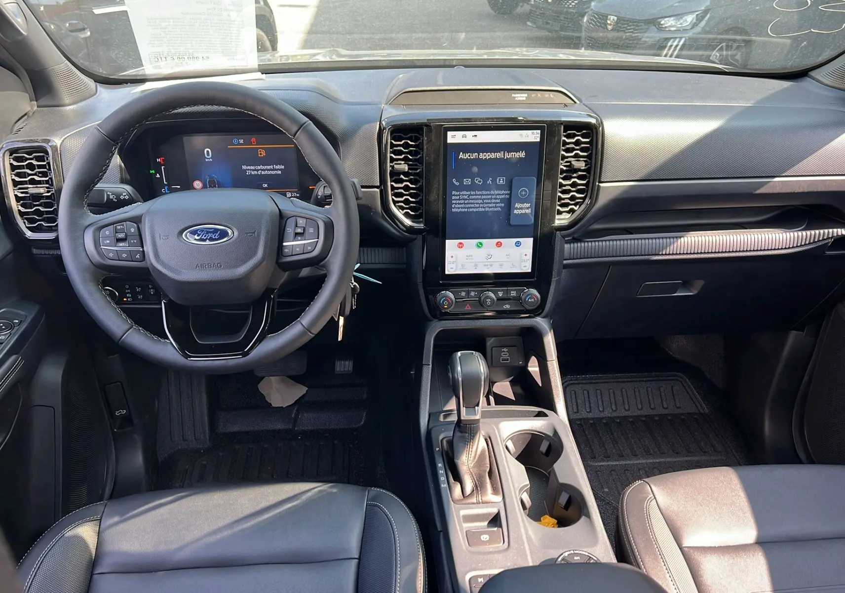 Intérieur du Ford Ranger 2025 vu de face, tableau de bord noir avec écran tactile vertical et volant multifonctions.