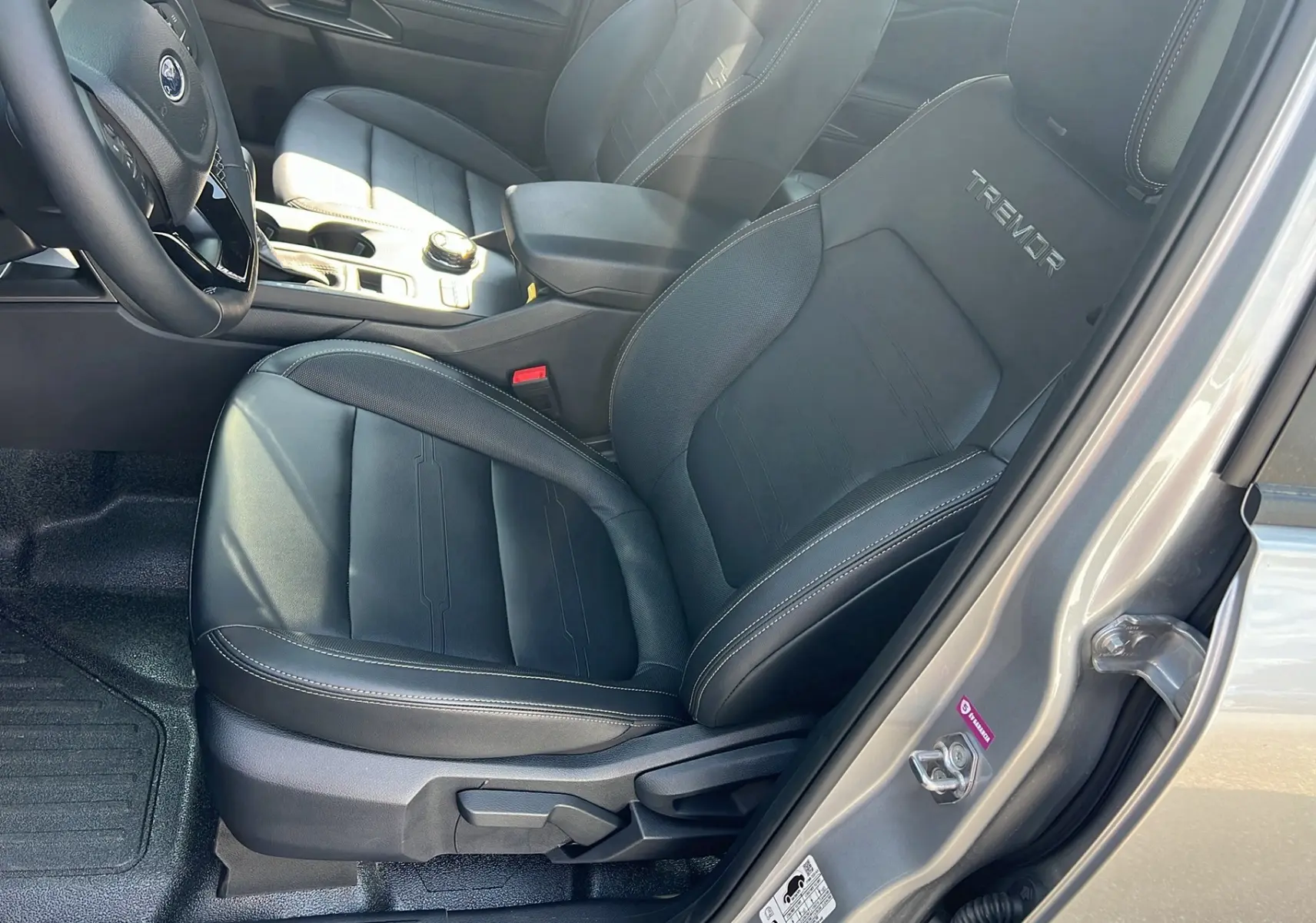 Intérieur côté conducteur du Ford Ranger 2025 gris iconic, siège en cuir noir avec logo Tremor brodé sur l'appuie-tête.
