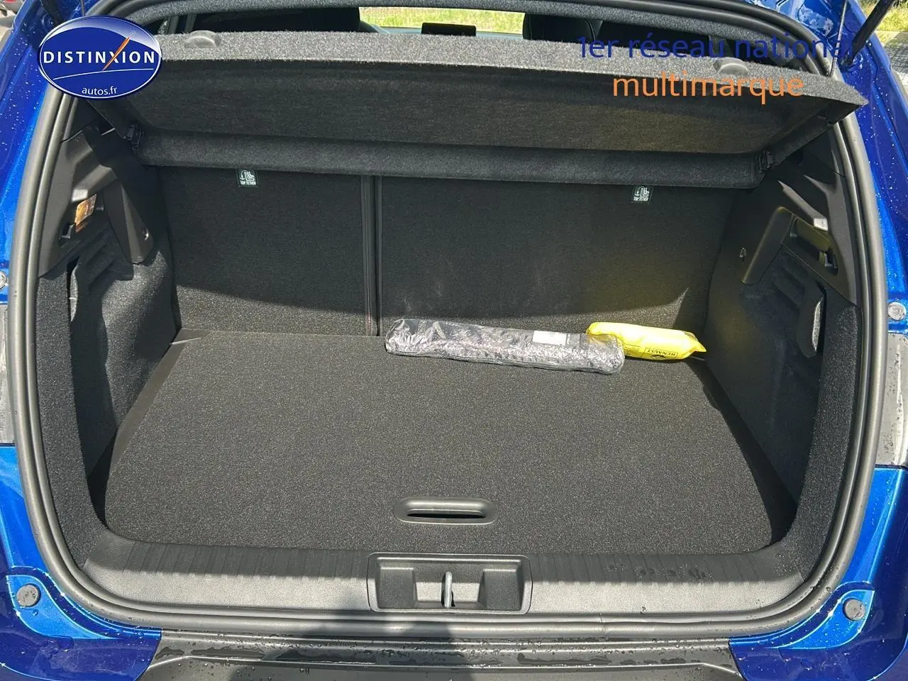 Coffre ouvert d’un Renault Captur bleu iron 2025, montrant un espace de rangement propre et spacieux.