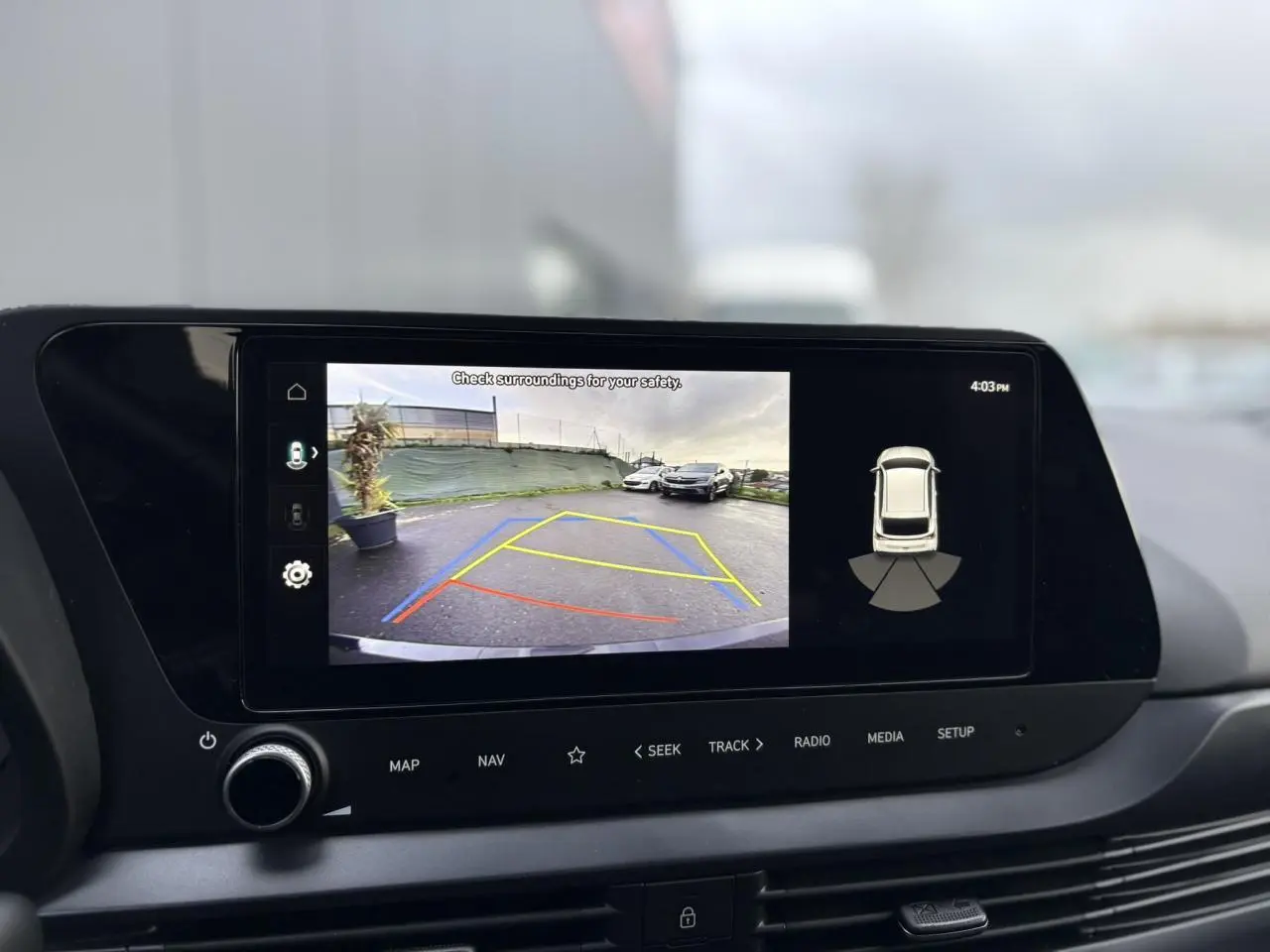 Vue rapprochée de l'écran tactile intérieur affichant la caméra de recul et l'aide au stationnement du Hyundai i20 noir Phantom Metal.