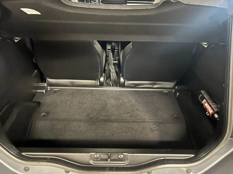 Vue intérieure du coffre arrière gris du Ligier JS50 Sport Elite E5+ 2025, avec sièges avant et bouteille d'huile visible.