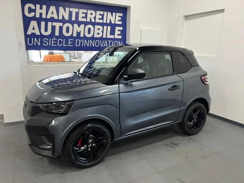 Vue 3/4 avant droite d'une LIGIER JS50 SPORT ELITE E5+ gris métallisé avec jantes noires, en intérieur showroom.