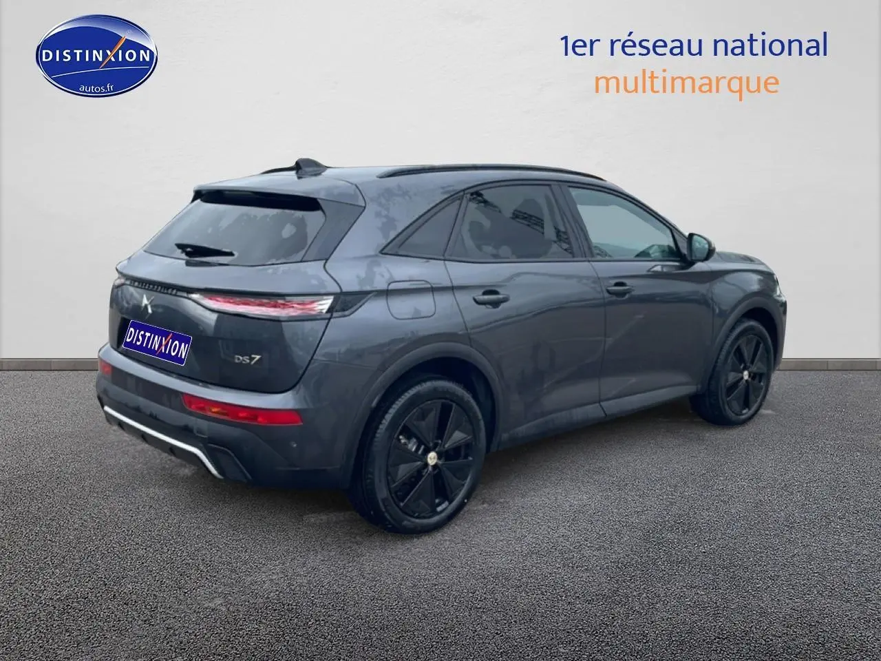 Vue 3/4 arrière droite d’un DS7 gris titane avec jantes noires et feux arrière LED allumés.