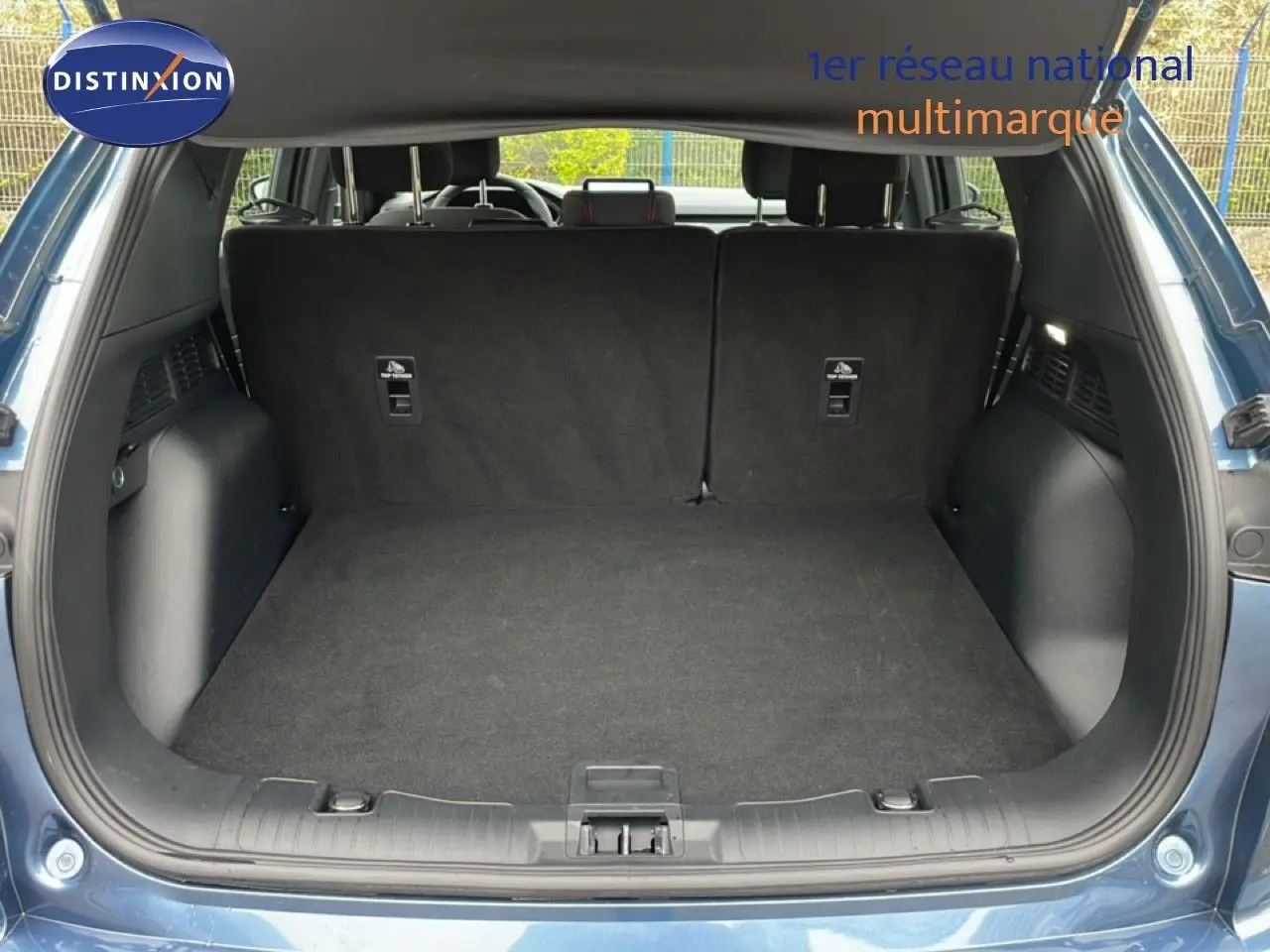 Vue arrière du coffre ouvert du Ford Kuga 2024 bleu vapor metal, montrant un espace de chargement propre et spacieux.