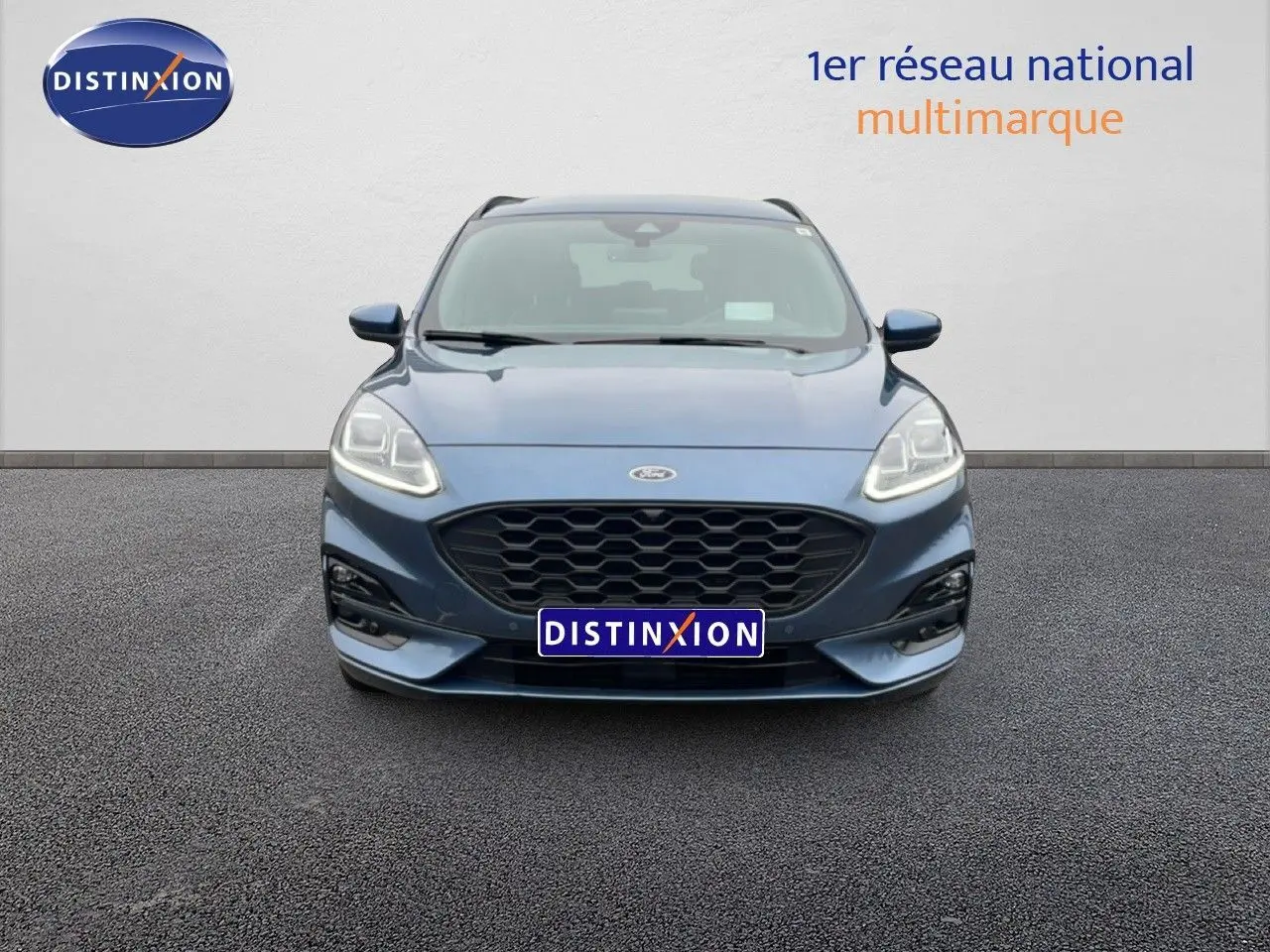 Vue avant d'un Ford Kuga 2024 bleu vapor metal avec calandre noire et phares LED allumés.