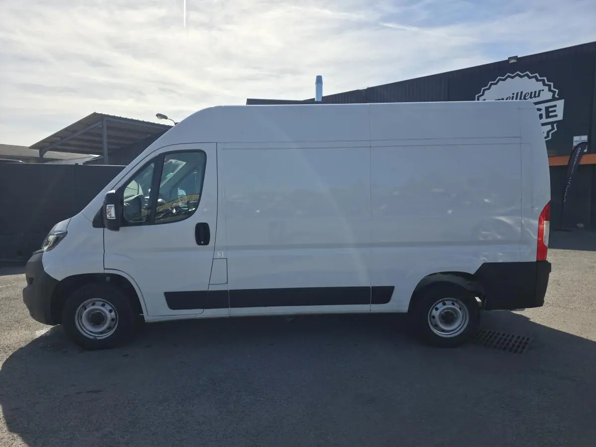 Vue de profil côté gauche d’un fourgon FIAT Ducato blanc 2023 avec porte latérale coulissante et jantes acier.