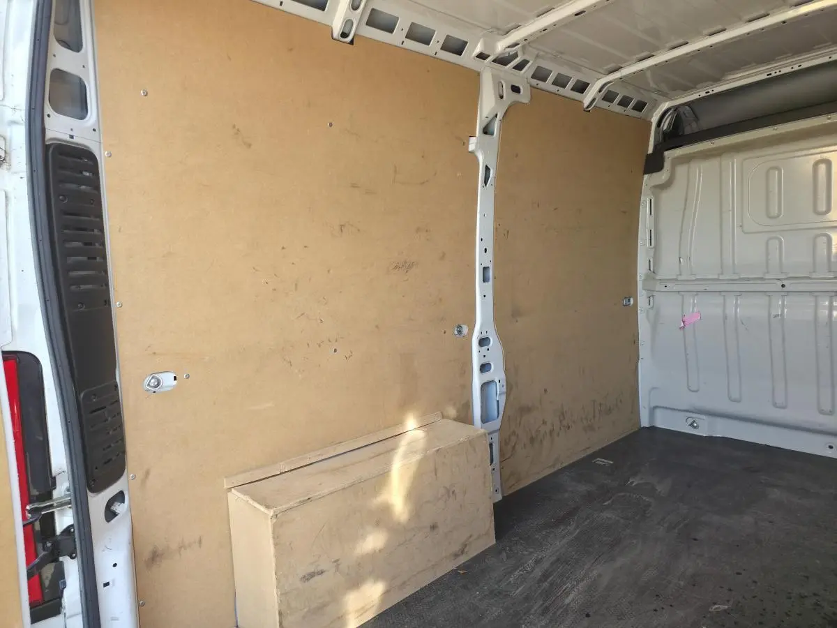 Vue intérieure arrière du fourgon blanc FIAT Ducato tôlé 3.5 M avec parois en bois et sol noir usé.