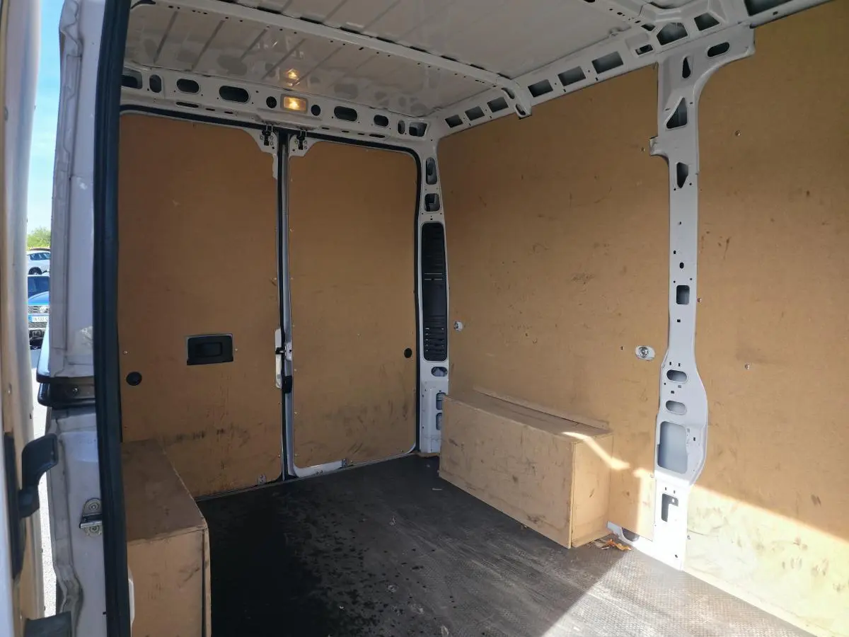 Vue intérieure arrière du fourgon blanc FIAT Ducato tôlé 2023, montrant la cloison et le revêtement bois des parois.
