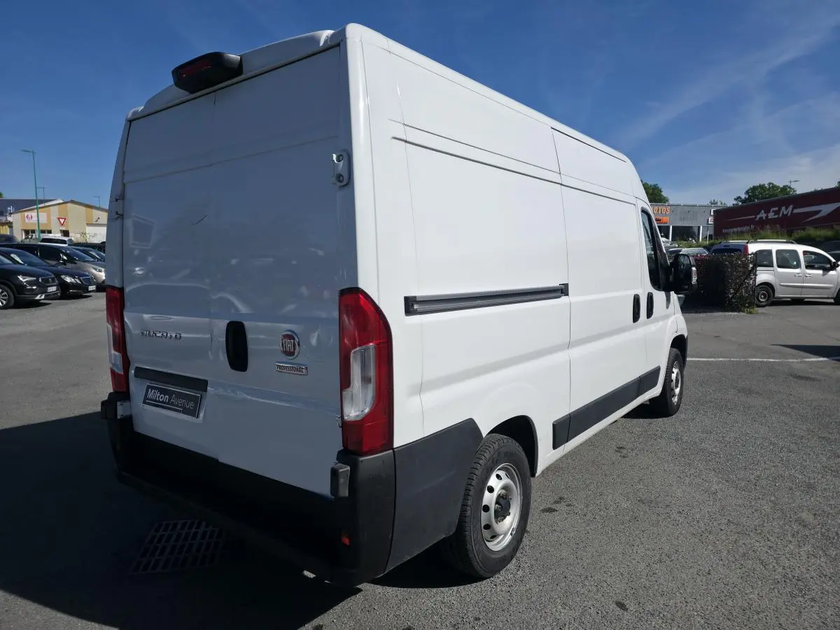 Vue 3/4 arrière droite d'un FIAT Ducato Fourgon blanc 2023 avec portes arrière tôlées et jantes acier 15 pouces.
