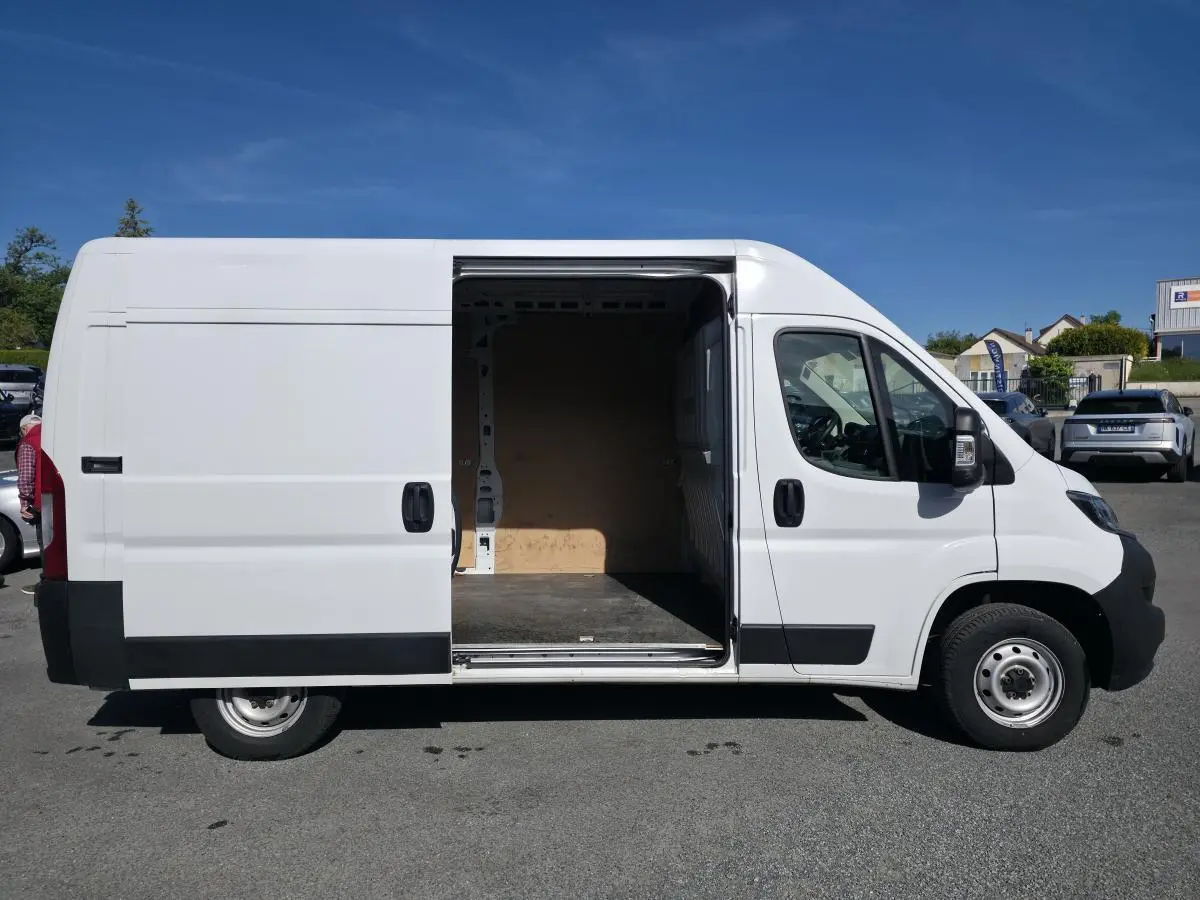Vue de profil droit du FIAT Ducato Fourgon blanc 2023 avec porte latérale coulissante ouverte montrant l'intérieur vide.