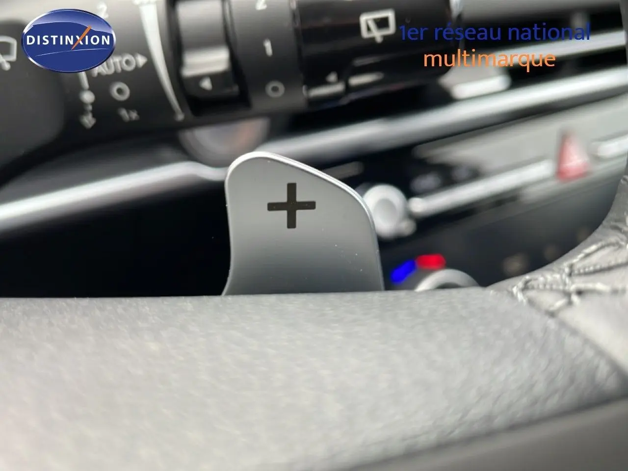 Gros plan sur la palette de changement de vitesse "+" du volant du Hyundai Tucson blanc Atlas, intérieur noir.