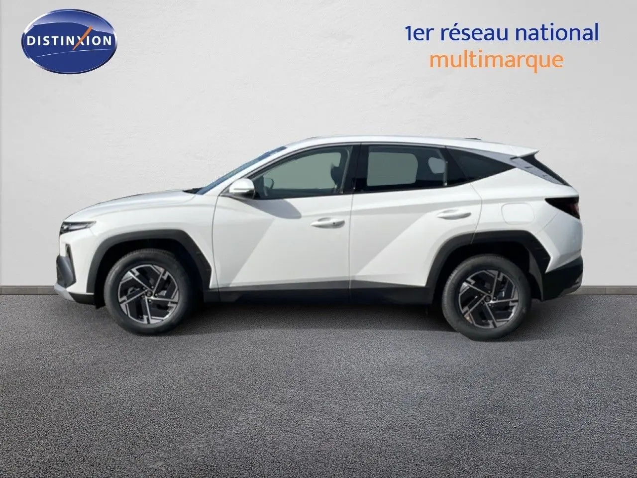 Vue de profil côté gauche d'un Hyundai Tucson blanc Atlas 2026 avec jantes bi-ton et lignes anguleuses marquées.