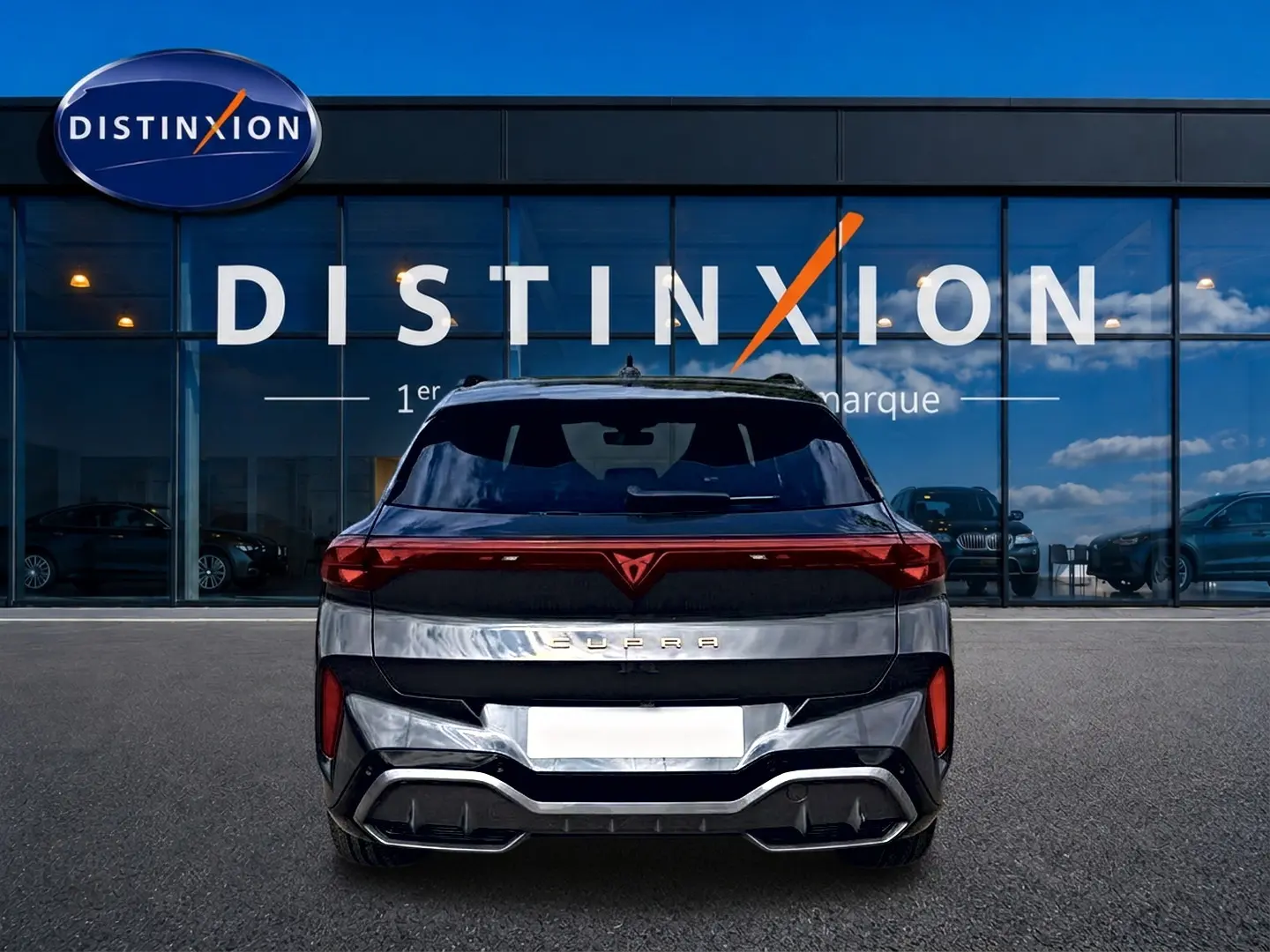 Vue arrière d'un CUPRA TERRAMAR gris timanfaya avec feux LED et diffuseur noir, stationné devant un showroom Distinxion.
