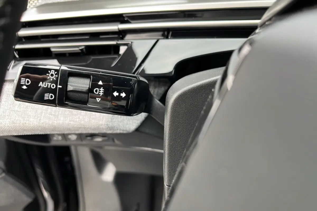 Gros plan sur la commande des feux et clignotants à gauche du volant dans l'habitacle du Peugeot 3008 Hybrid 2025.