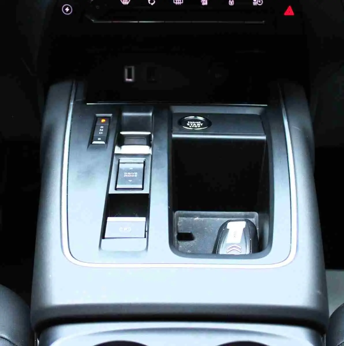 Gros plan sur la console centrale noire du Citroën C5 Aircross hybride, avec bouton start et commandes de boîte automatique.