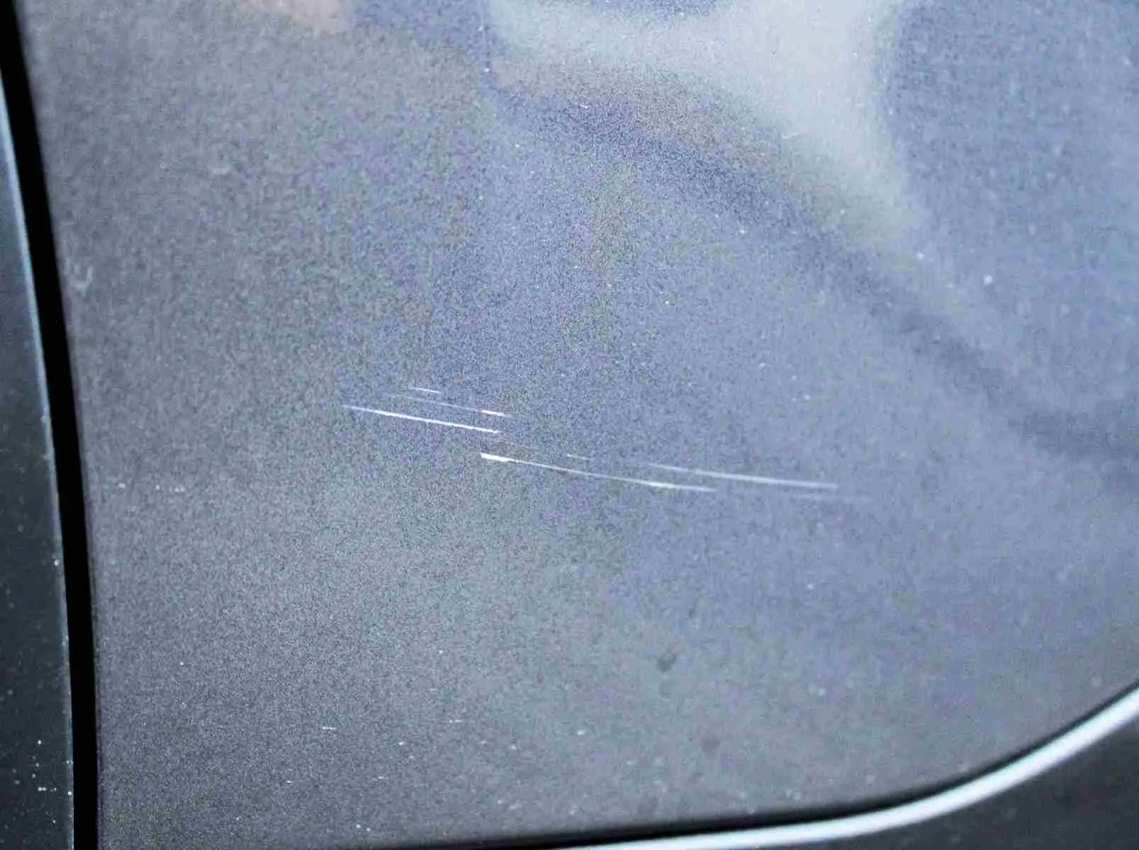 Gros plan sur une rayure fine sur la porte côté gauche d'un Citroën C5 Aircross gris platinium hybride rechargeable.