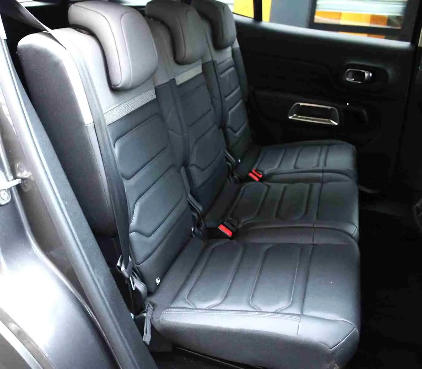 Vue latérale des sièges arrière en cuir noir du Citroën C5 Aircross gris platinium, avec ceinture et appuie-têtes visibles.