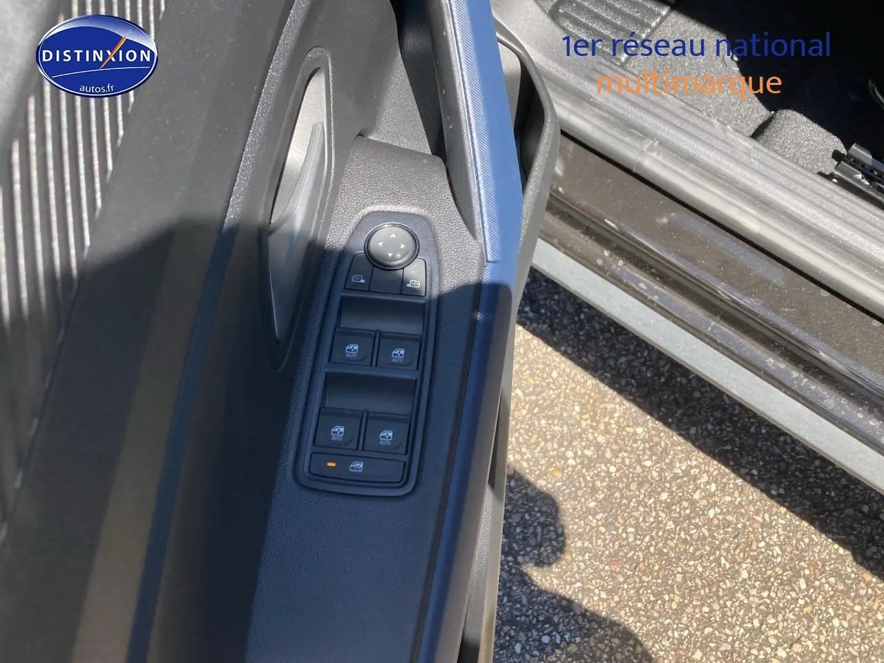 Vue rapprochée de la porte avant gauche du Dacia Duster noir, montrant les commandes électriques des vitres.