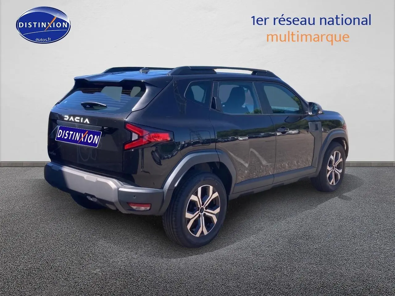 Vue 3/4 arrière droite du Dacia Duster noir 2025 avec jantes alu et barres de toit visibles.