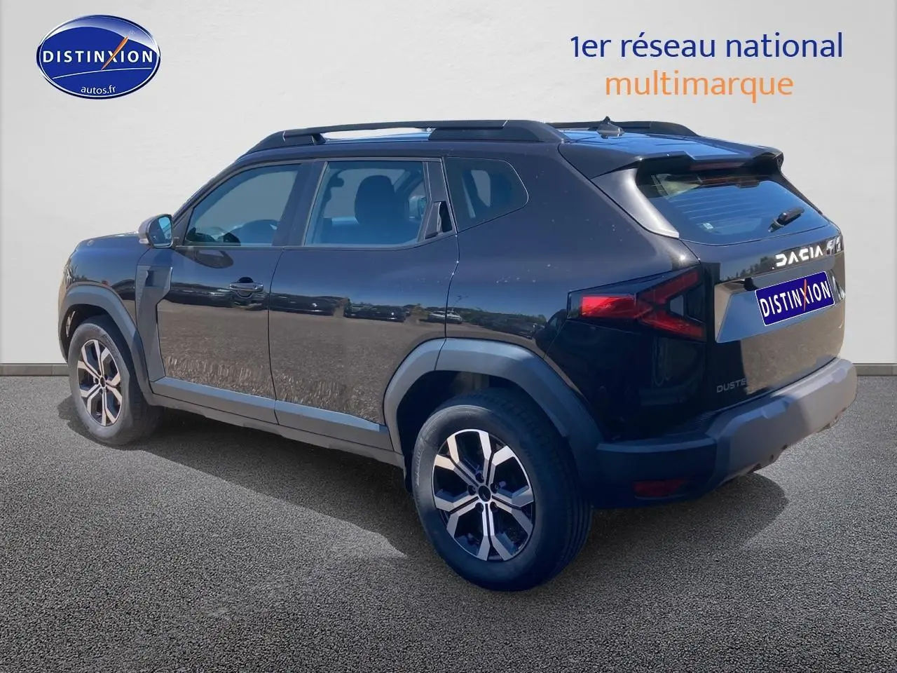 Vue 3/4 arrière droite du Dacia Duster noir 2025 avec jantes alliage et barres de toit visibles.