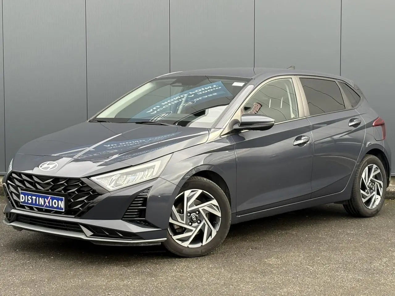 Vue 3/4 avant droite de la Hyundai i20 2025 gris Aurora Metal avec jantes alliage diamantées et calandre noire.