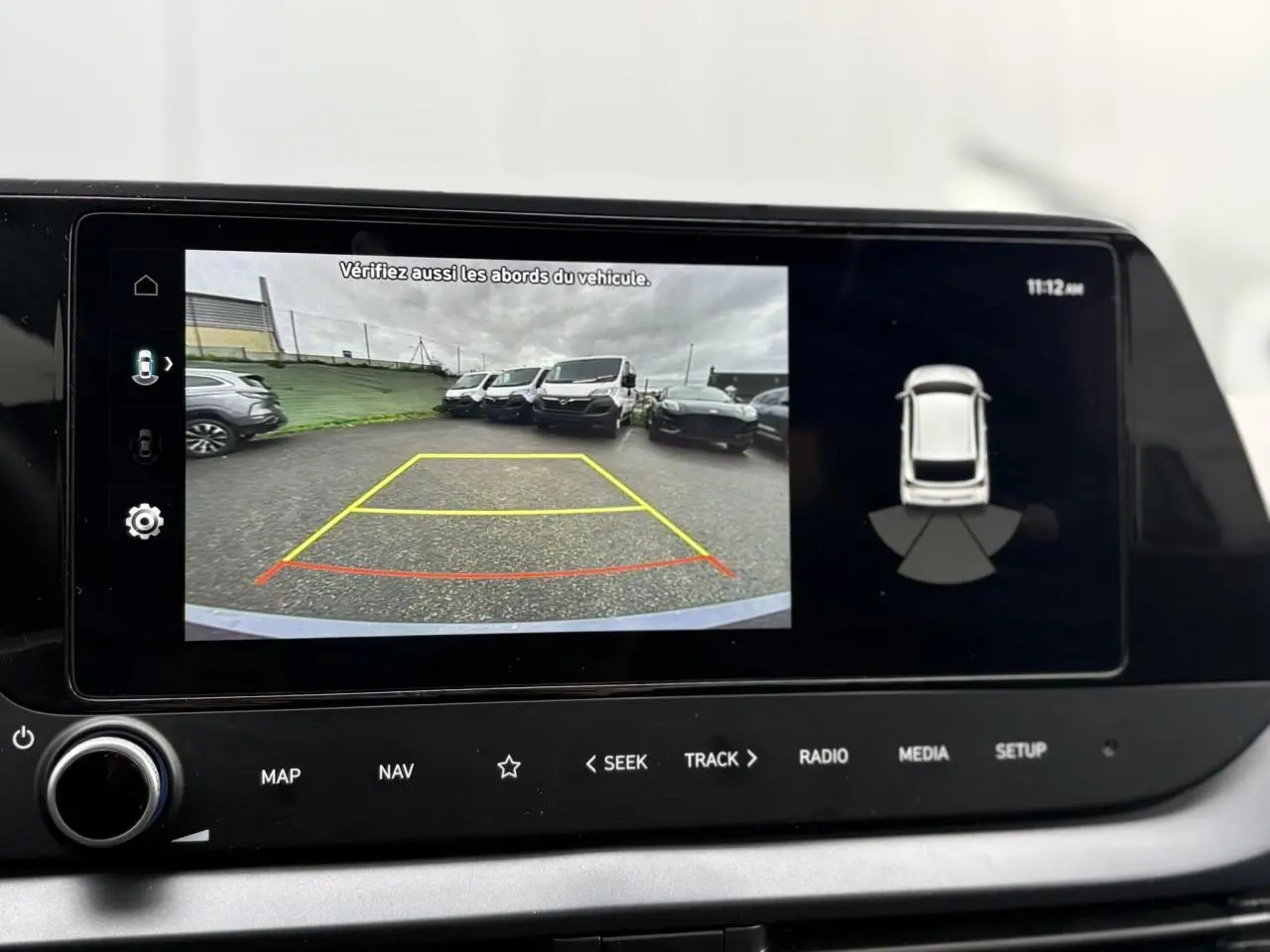 Écran tactile intérieur montrant la caméra de recul et l'affichage du système d'aide au stationnement du Hyundai i20 gris Aurora Metal.