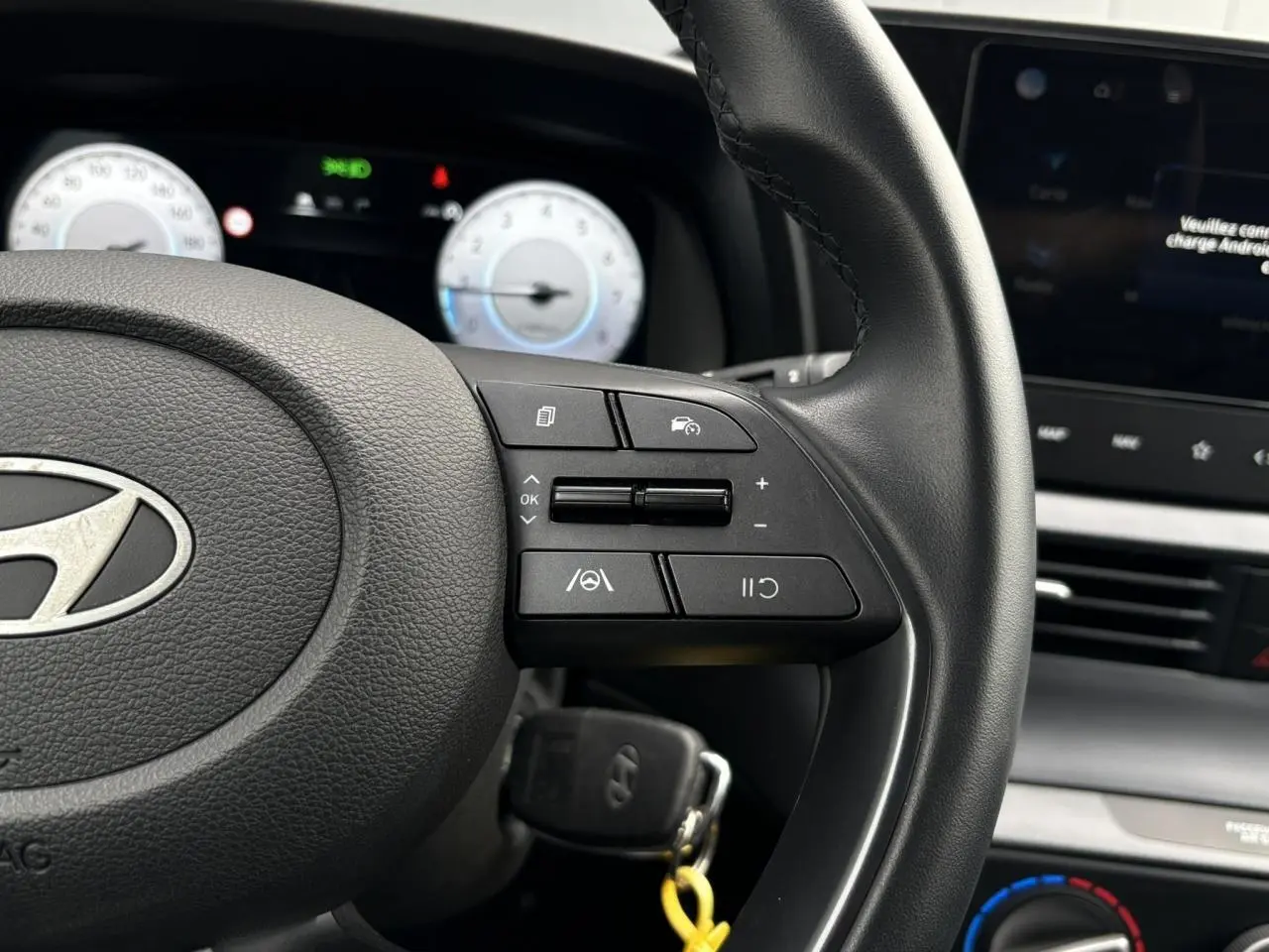 Gros plan sur le volant cuir de la Hyundai i20 2025 avec commandes au volant et tableau de bord numérique.