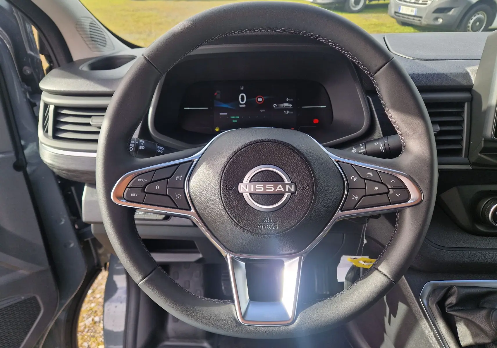 Vue rapprochée du volant noir du Nissan Primastar 2025 avec commandes intégrées et tableau de bord numérique.