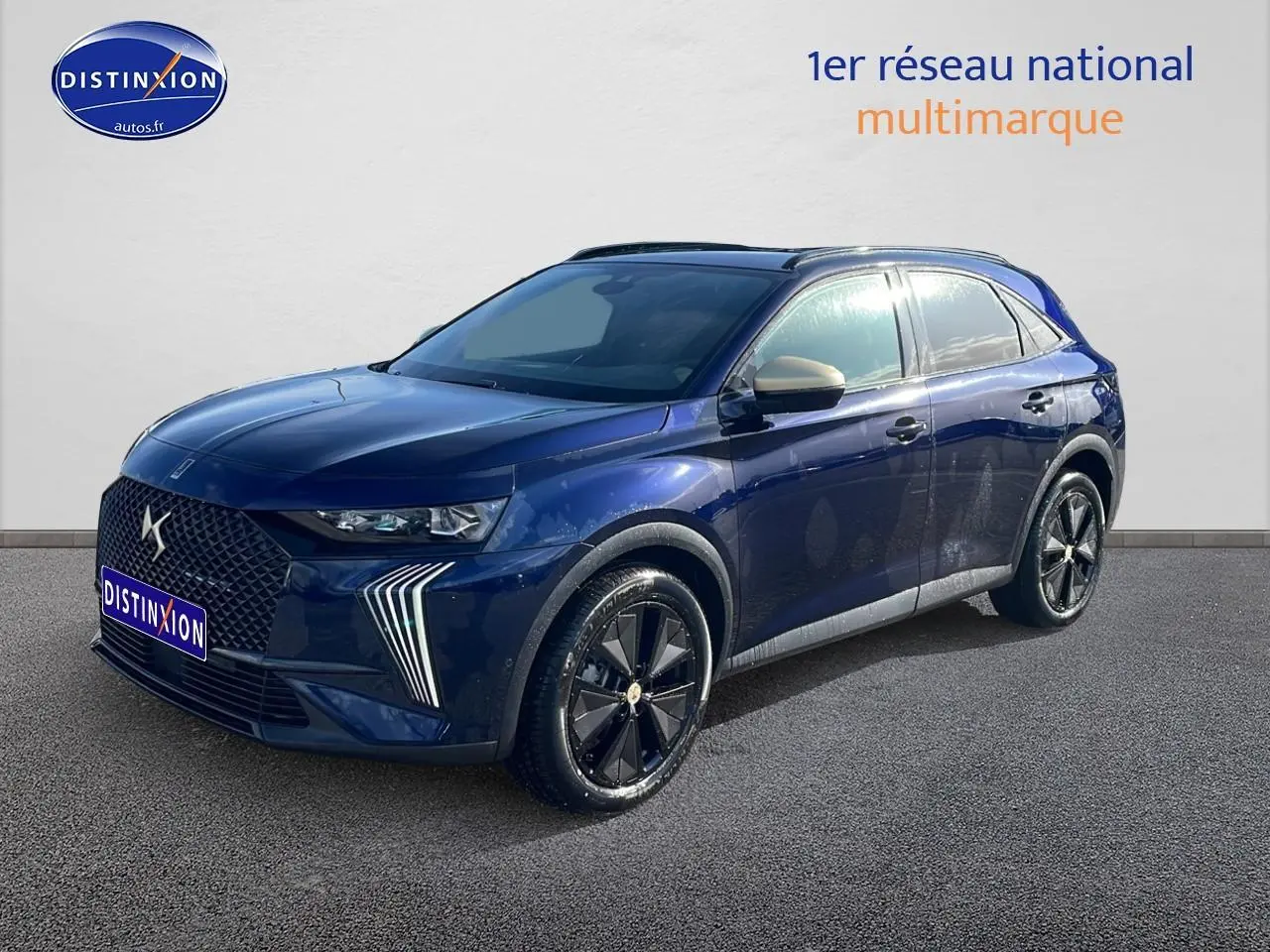 DS7 bleu 3/4 avant droit avec calandre distinctive et jantes noires brillantes sur fond neutre.