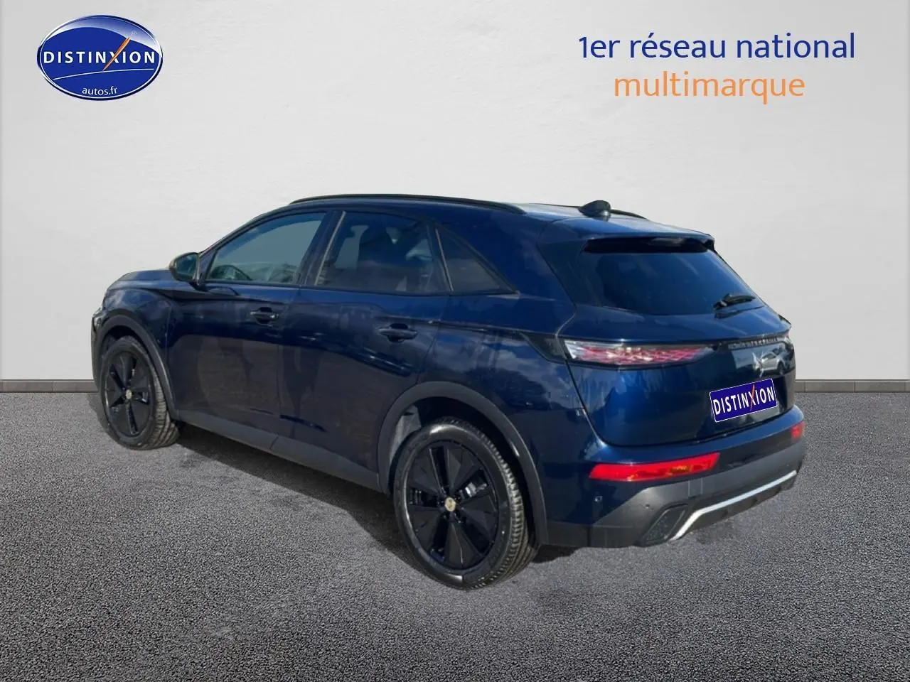 Vue 3/4 arrière droite d'un DS7 bleu foncé avec jantes noires et vitres arrière surteintées sur fond neutre.