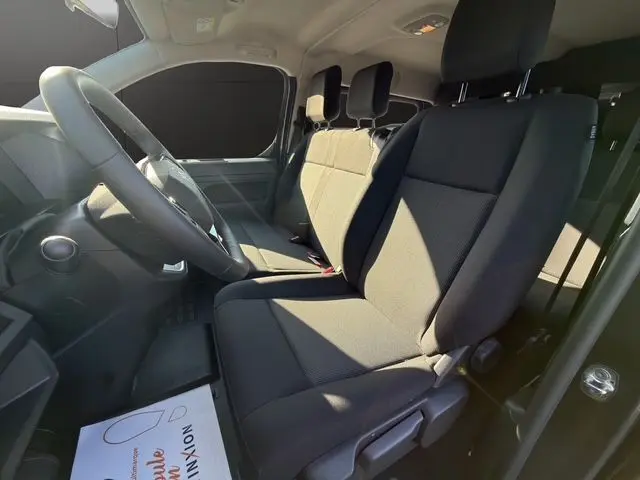 Vue intérieure côté conducteur du Citroën Jumpy gris titane, montrant les sièges avant et le volant.