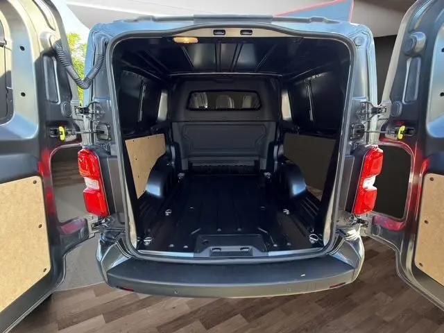 Vue arrière ouverte du Citroën Jumpy gris titane, montrant l'espace de chargement vide et les portes battantes ouvertes.