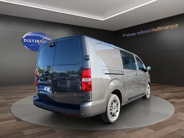 Vue 3/4 arrière droite du Citroën Jumpy gris titane avec portes arrière fermées dans un showroom.