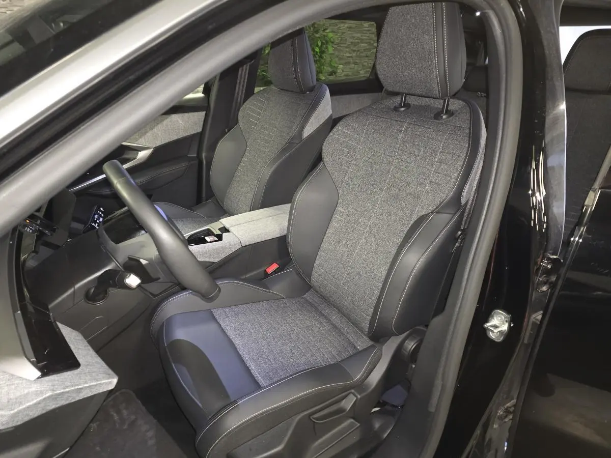 Vue intérieure côté conducteur du Peugeot 5008 noir 2025, sièges tissu gris et cuir noir avec surpiqûres quartz.
