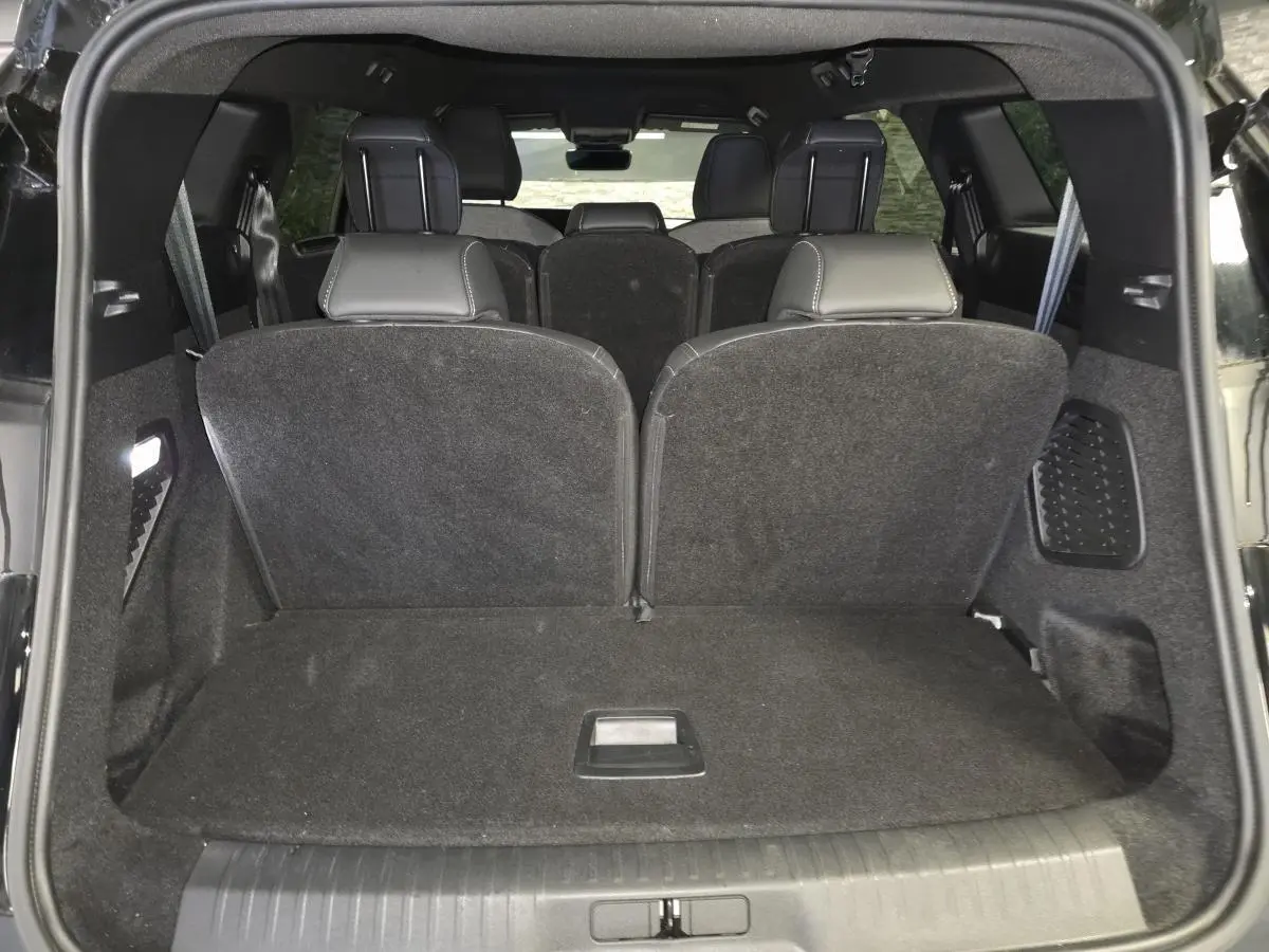 Vue arrière du coffre noir du Peugeot 5008 2025 avec sièges rabattus et habillage intérieur sombre.