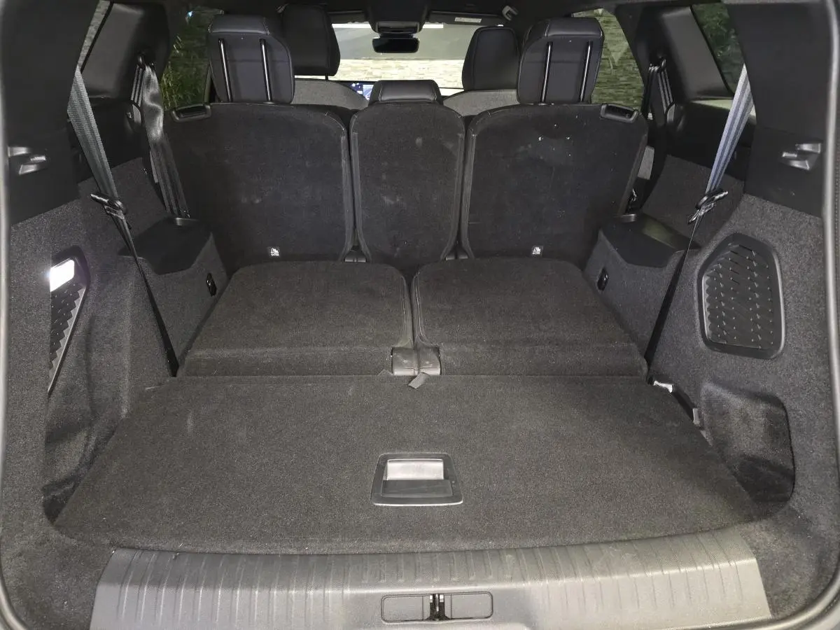 Vue du coffre arrière du Peugeot 5008 noir 2025 avec banquette arrière partiellement rabattue et espace de chargement plat.