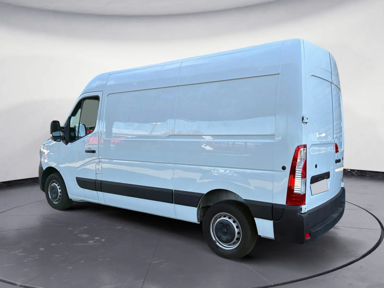 Vue 3/4 arrière gauche d’un fourgon blanc Renault Master L2H2 2024 avec bande noire latérale et feux arrière verticaux.