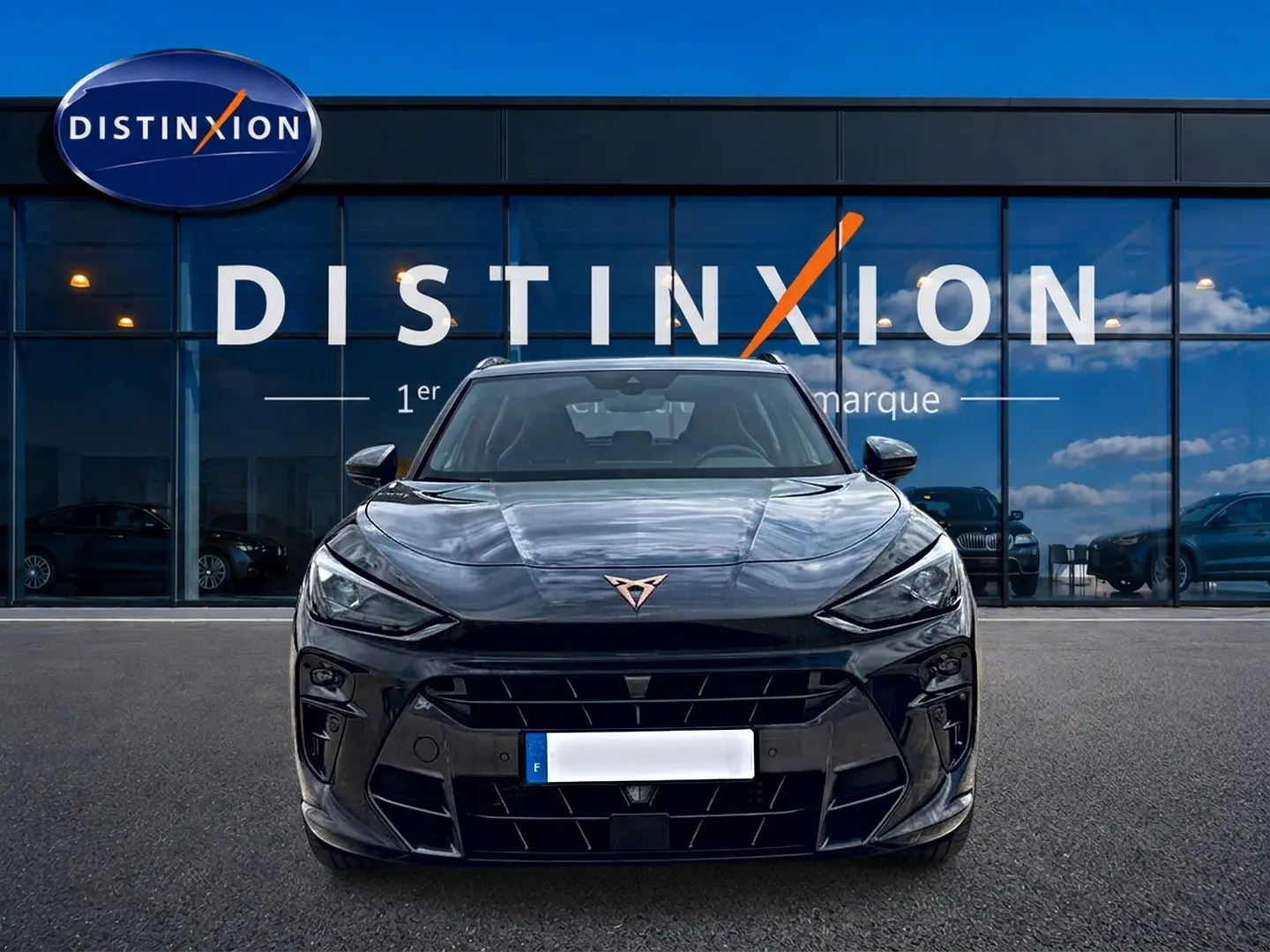 Vue frontale d'un CUPRA TERRAMAR gris Timanfaya avec logo cuivré, devant une vitrine Distinxion.