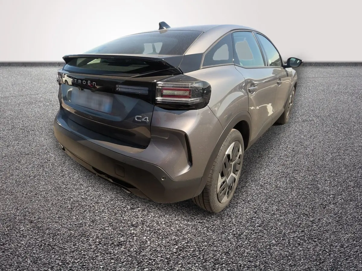 Vue 3/4 arrière droite d'une Citroën C4 hybride gris foncé avec feux arrière LED et spoiler de coffre.