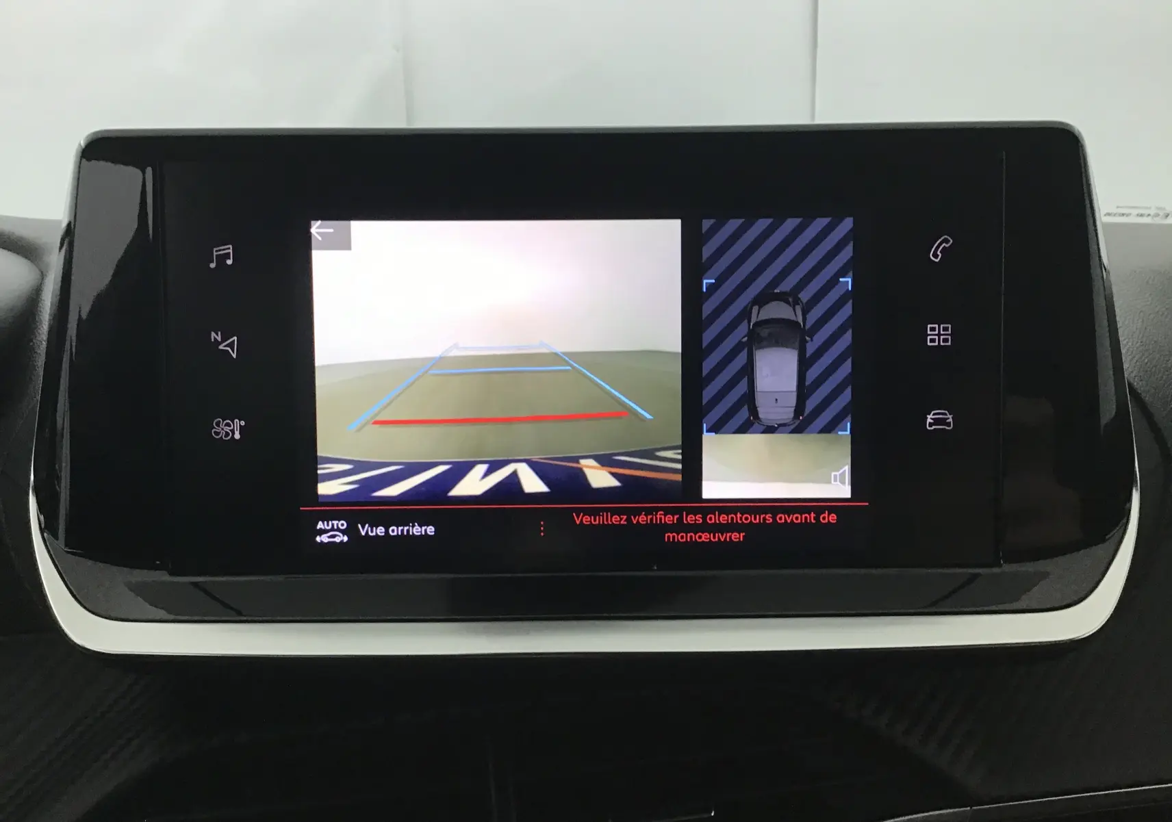 Écran central de la Peugeot 208 2022 montrant la caméra de recul avec guidage et vue aérienne du véhicule noir.