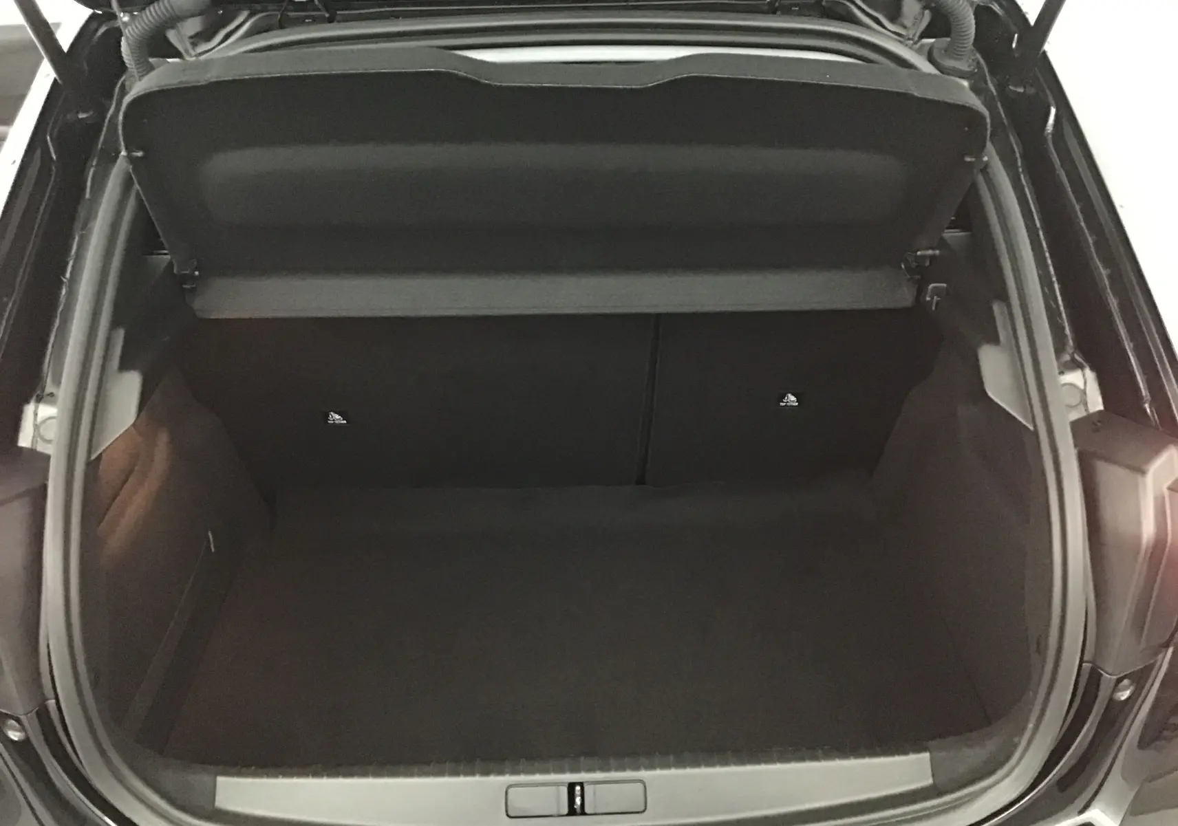 Coffre ouvert de la Peugeot 208 noire 2022, vue plongeante montrant l'espace de rangement vide et propre.