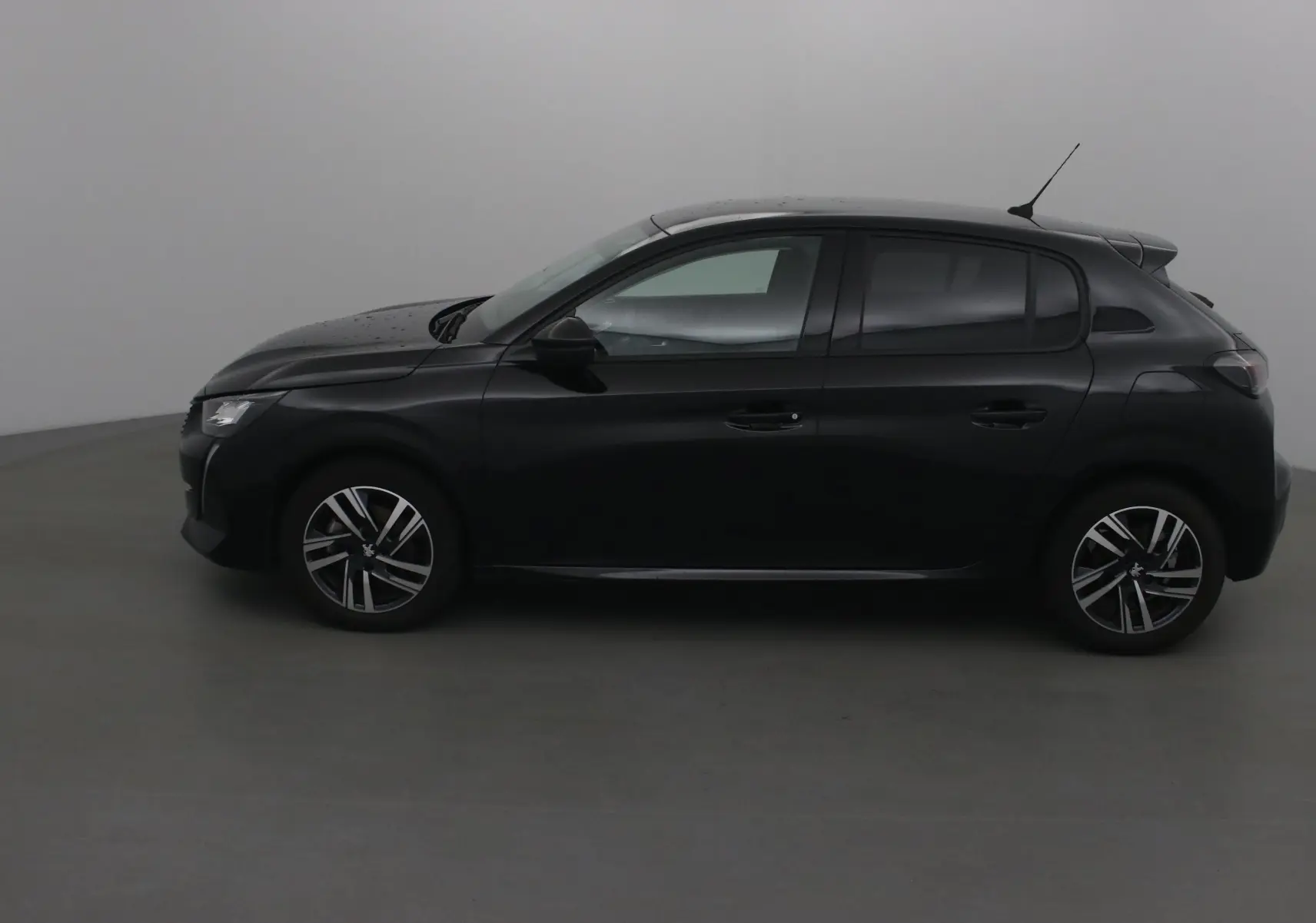Profil côté gauche d'une Peugeot 208 noire 2022, version 1.2 PureTech 100 Allure avec jantes alliage et antenne toit.