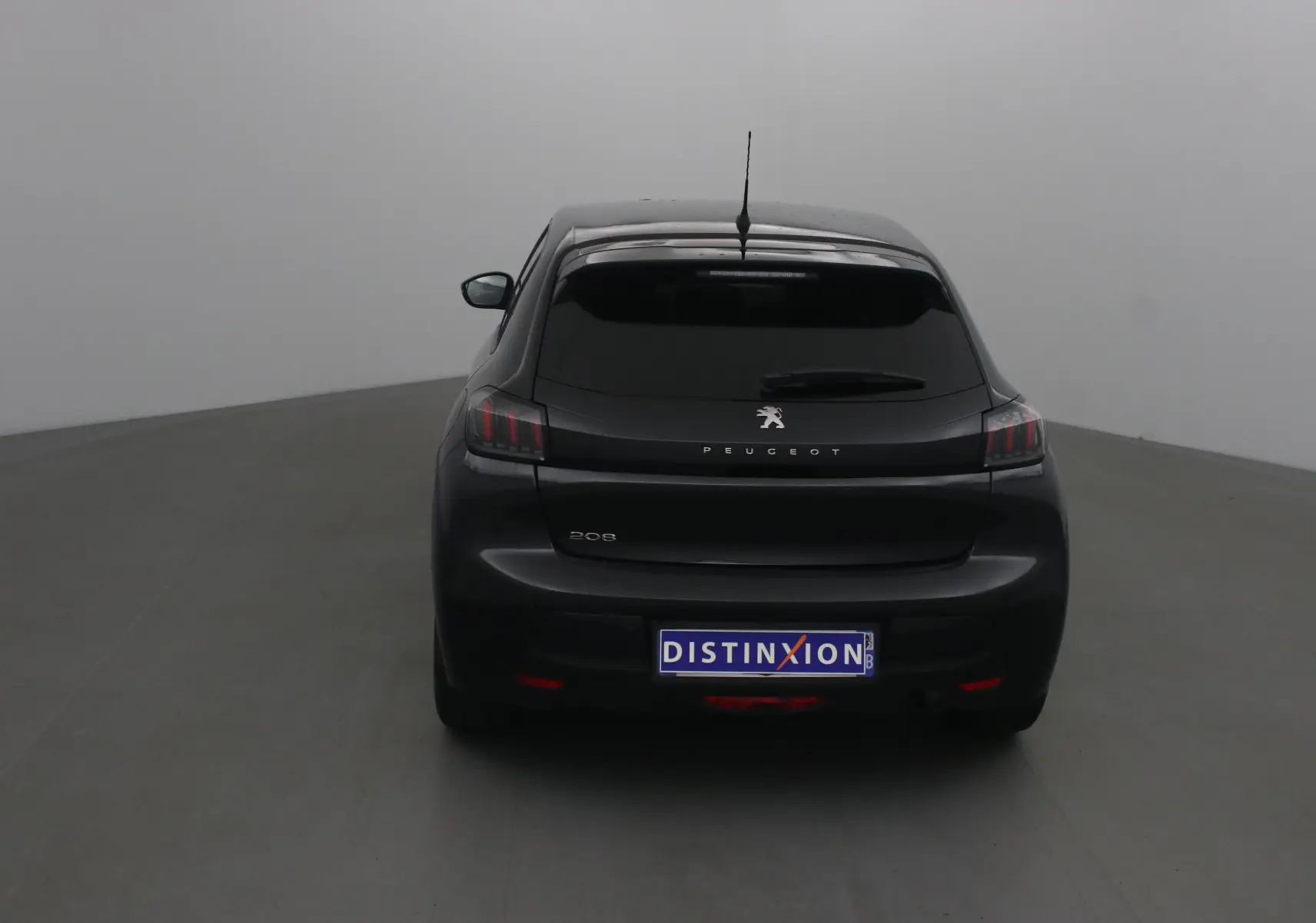 Vue arrière d'une Peugeot 208 noire de 2022 avec feux arrière à griffes et vitre arrière teintée.