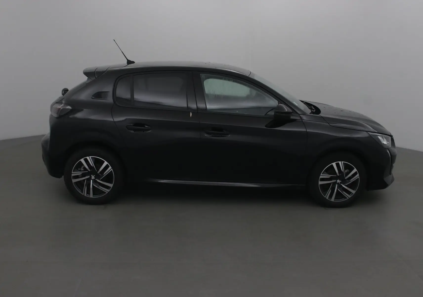Profil côté gauche d'une Peugeot 208 noire 2022, finition Allure avec jantes alliage et vitres teintées.