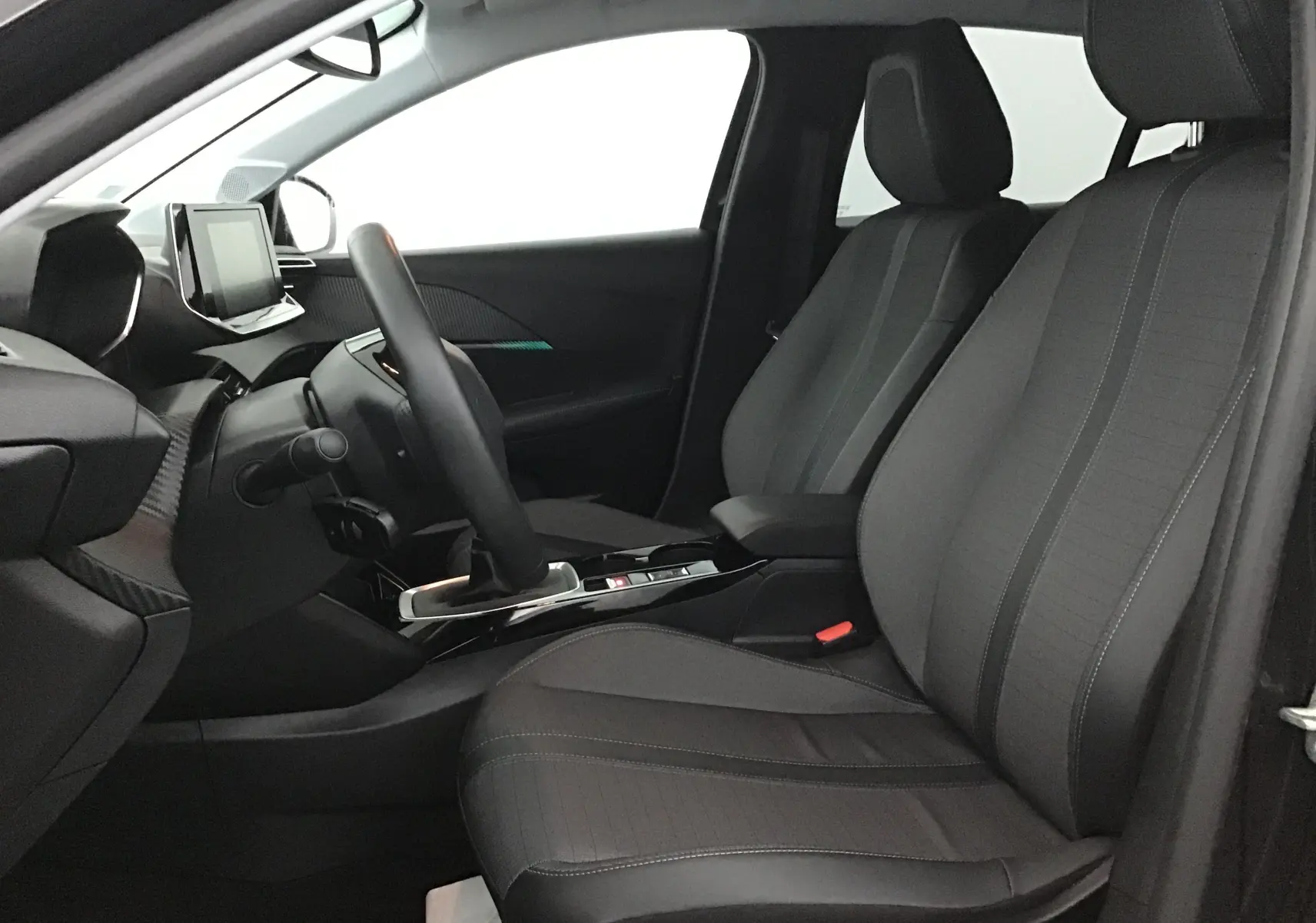 Intérieur noir de la Peugeot 208 2022, vue côté conducteur, avec sièges tissu et tableau de bord moderne.