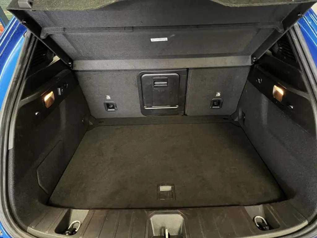 Coffre ouvert de l'Alfa Romeo Tonale bleu, montrant l'espace de chargement et la banquette arrière rabattable.