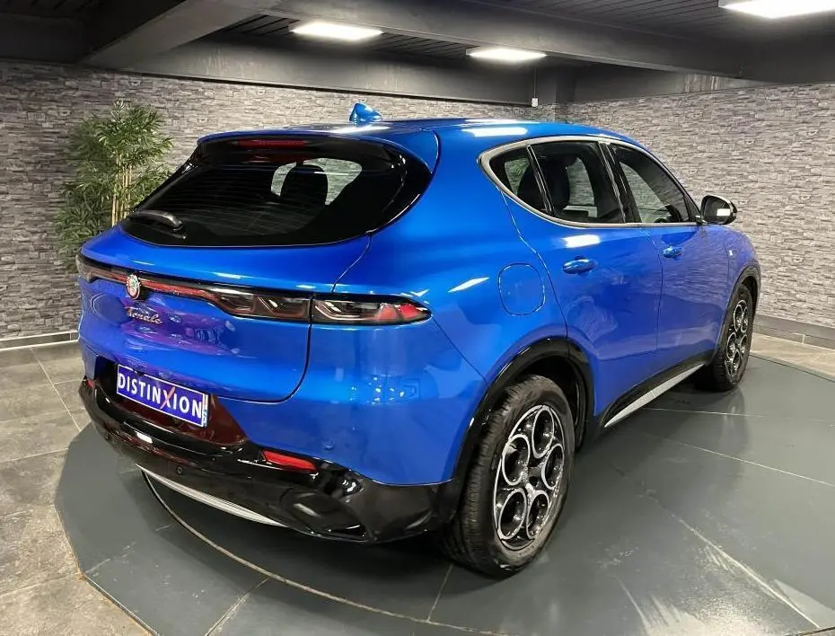 Vue 3/4 arrière droite d'une Alfa Romeo Tonale bleu métallisé avec jantes 18 pouces et toit noir brillant.